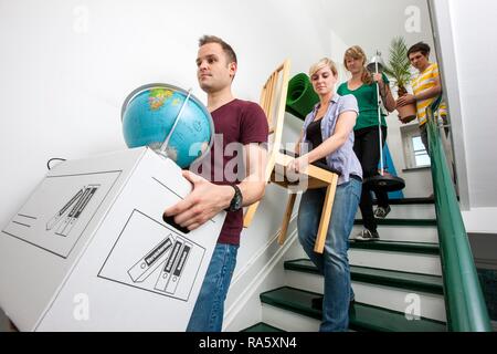 Private house move, friends helping, carrying boxes and furniture down a staircase Stock Photo