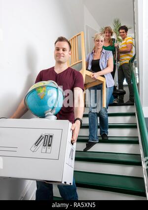 Private house move, friends helping, carrying boxes and furniture down a staircase Stock Photo