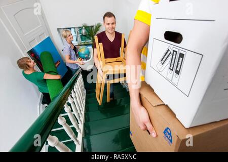 Private house move, friends helping, carrying boxes and furniture up the stairs Stock Photo