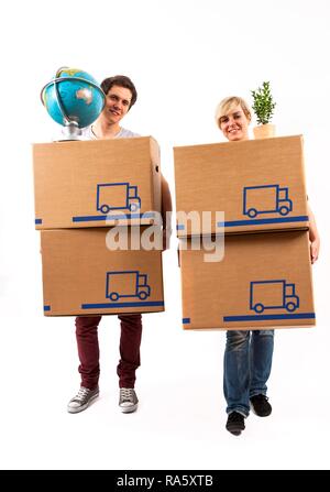 Young couple carrying moving boxes, a globe and a house plant Stock Photo