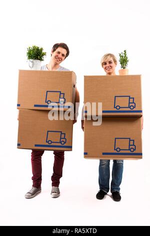 Young couple carrying moving boxes and house plants Stock Photo