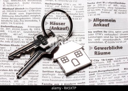 Two keys with a metal key tag shaped like a house lying on the real estate page of a German daily newspaper Stock Photo