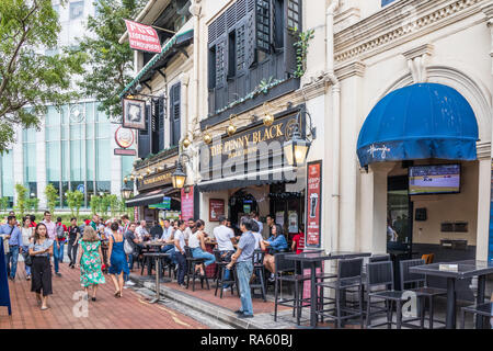 Singapore - 14th December 2018: People drinking in pubs on Boat Quay. The street is popular with both tourists and expats. Stock Photo