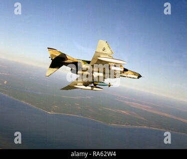 1976 - An air-to-air right underside view of an F-4E Phantom II aircraft equipped with an SUU dispenser on right wing, Pave Tack center mounted and an LGB-10 Mark 84 on left wing. Stock Photo