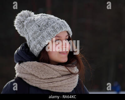 Happy young woman  in winter hat and scarf in the winter park in sunny day Stock Photo