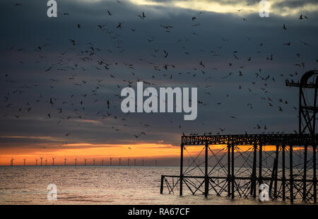Brighton UK 1st January 2019 - The sun sets behind the West Pier with the Rampion wind farm in the distance at the end of beautiful afternoon on the south coast of Britain Credit: Simon Dack/Alamy Live News Stock Photo