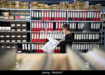 Bad Arolsen, Germany. 11th Dec, 2018. Christian Groh, head of the Archive Department, leafs through a file in front of a file cabinet in the provisional archive of the International Tracing Service (ITS). The ITS is an archive and documentation centre on Nazi persecution and the liberated survivors. (to dpa 'International Tracing Service ITS' from 02.01.2019) Credit: Swen Pförtner/dpa/Alamy Live News