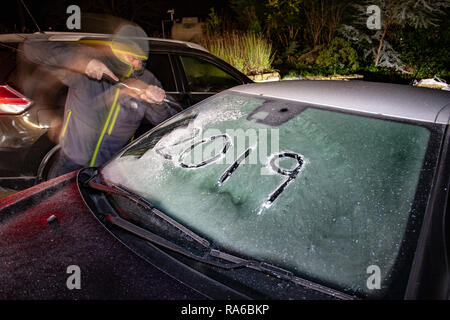 Lixwm, North Wales UK. 2nd Jan, 2019. UK Weather: A severe drop in temperatures overnight and the first frost of 2019 as a motoroist begins quickly to clear a windscreen of overnight frost in the village of Lixwm, Wales Credit: DGDImages/Alamy Live News Stock Photo