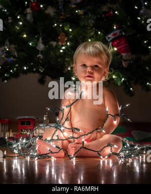 Little Boy/Baby in Christmas Lights under the Tree Stock Photo