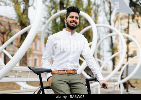 portrait of indian young man sitting on bike with mobile phone in the street Stock Photo