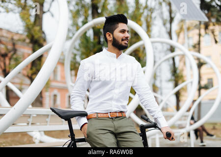portrait of indian young man sitting on bike with mobile phone in the street Stock Photo