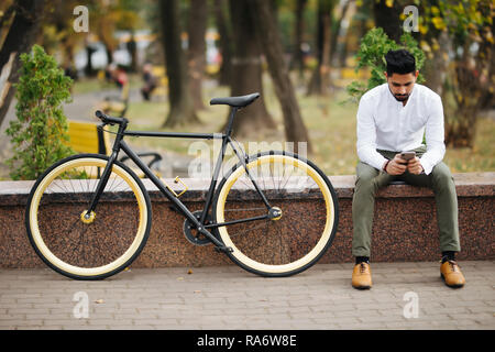 Lifestyle, transport, communication and people concept - young man with bicycle and smartphone on city street Stock Photo