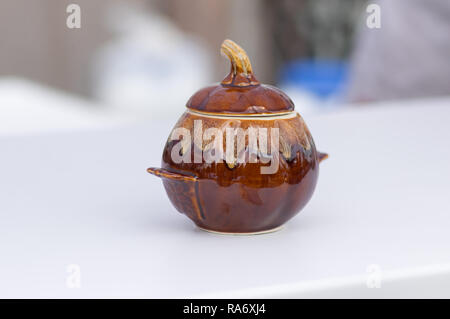 Earthenware pot made in shape of pumpkin standing on a light surface Stock Photo