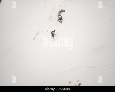 freerider snowboarder down the steep slope of white snow and trees in the mountains of the Caucasus Stock Photo