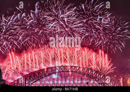 Bright red balls over the top of Sydney Harbour bridge arch against black dark sky during new year midnight fireworks celebrating annual event. Stock Photo