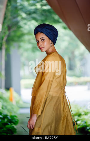 Portrait of a young, beautiful, tall and elegant Muslin Asian woman in a turban and stylish minimalist outfit in Asia during the day. Stock Photo