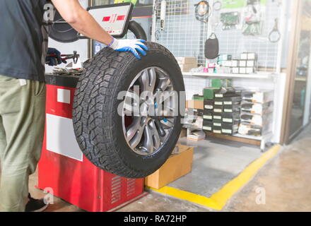 Mechanic balancing a car wheel on an automated machine at the garage. Stock Photo