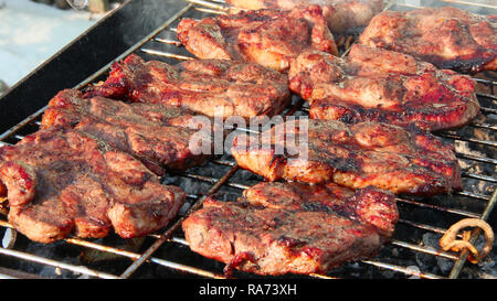 Steak grilling on fire. Process of cooking meat. Steak on barbecue. Preparation of appetizing pork outside. Cooking of pork meat. Barbecue lunch outdo Stock Photo