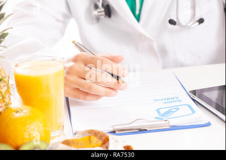 Nutritionist doctor writing diet plan on table. Stock Photo