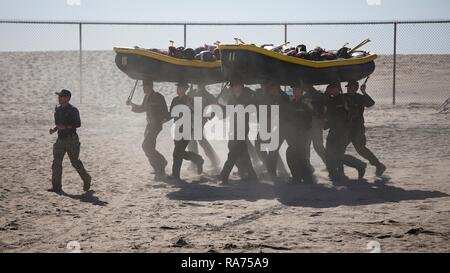 U.S. Navy SEAL candidates team carry assault rafts during Basic Underwater Demolition SEAL training at the Navy Special Warfare Center April 9, 2018 in Coronado, California. SEALs are the maritime component of U.S. Special Forces and are trained to conduct a variety of operations from the sea, air and land. Stock Photo