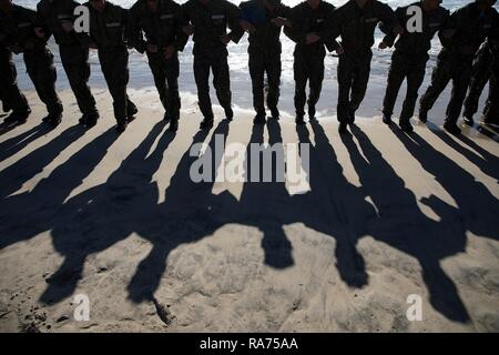 U.S. Navy SEAL candidates back into the surf during Basic Underwater Demolition SEAL training at the Navy Special Warfare Center April 9, 2018 in Coronado, California. SEALs are the maritime component of U.S. Special Forces and are trained to conduct a variety of operations from the sea, air and land. Stock Photo