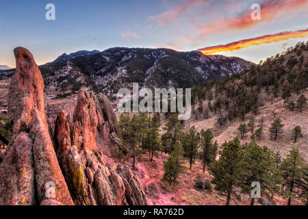 The winter sun sets behind Flagstaff Mountain, seen from the top of the Red Rock Fins in Settlers' Park in Boulder, Colorado. Stock Photo
