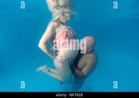 Pregnant woman and man, underwater fashion in a pool Stock Photo