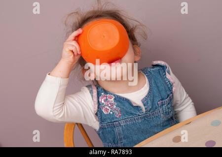 Three year old girl finishing snack from a bowl Stock Photo