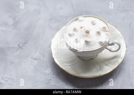 Coffee drink, marshmallows and cinnamon in a vintage white cup on a gray background Stock Photo