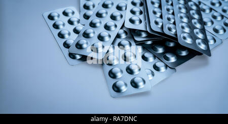Pile of tablets pill in blister packaging to protect medicine from light. Silver aluminium foil blister pack. Pharmaceutical industry. Pharmacy. Stock Photo