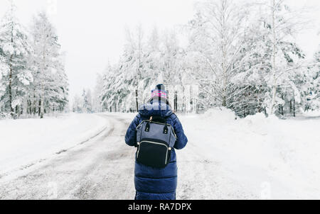Travel Lifestyle. Young woman with backpack in the winter walking along snowy road in sweden