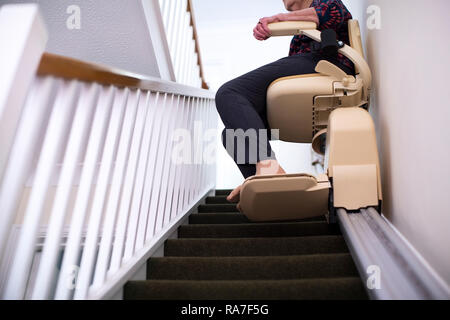 Detail Of Senior Woman Sitting On Stair Lift At Home To Help Mobility Stock Photo