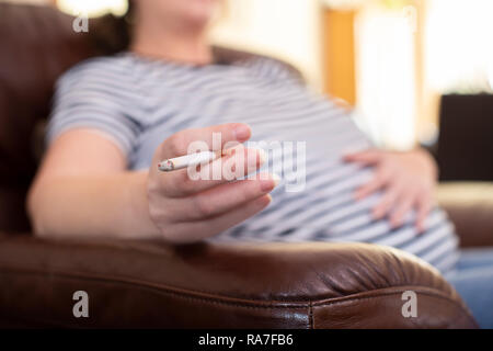 Close Up Of Pregnant Woman At Home Smoking Cigarette Stock Photo