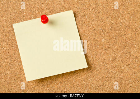 Empty yellow sticky paper memo note with red pin on cork board with copy space Stock Photo