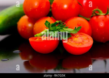 Isolated tomatoes, cucumbers and parsley vegetables on the kitchen table ready for making salad Stock Photo