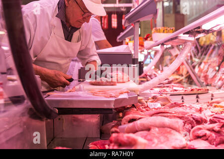 An Italian butcher cuts meat inside the central market in Torino, Italy Stock Photo