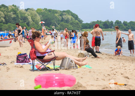 crowds of people fill a beach on a hot summer day Stock Photo