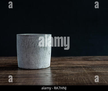 Empty modern concrete planter on wooden table isolated on black background with copy space. Stock Photo