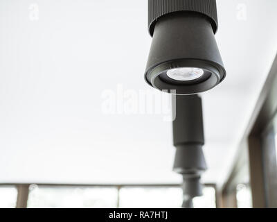 Black hanging light on ceiling in white room with copy space. Stock Photo