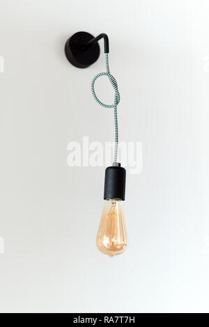 Edison retro lamp. Incandescent bulb on white wall background in loft. Concept of vintage style Stock Photo