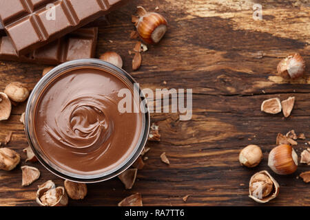 Chocolate spread with hazelnuts on wooden background Stock Photo