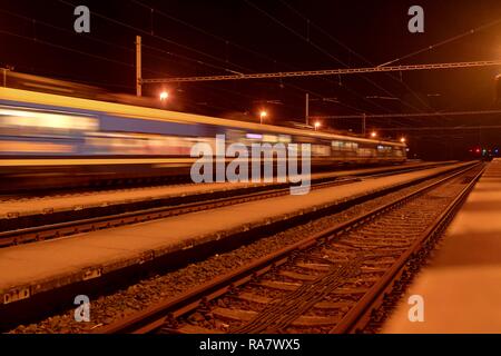 High speed passenger train on tracks with motion blur effect at night. Railway station in the Czech Republic Stock Photo