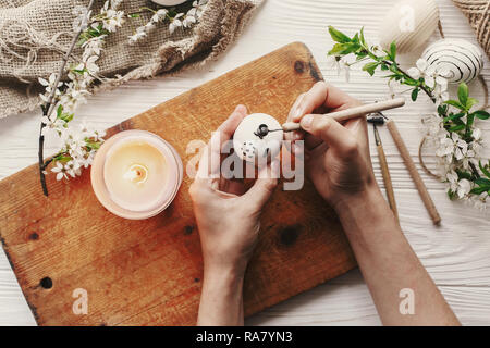 hand painting modern easter egg top view. preparation for holiday, easter celebration. stylish  painted egg. process of coloring eggs with wax and can Stock Photo