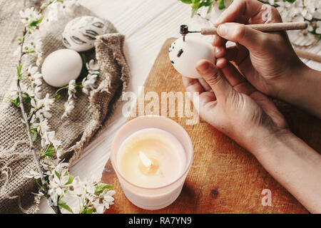 hand painting easter egg. preparation for holiday, easter celebration. stylish modern painted egg. process of coloring eggs with wax and candle. famil Stock Photo