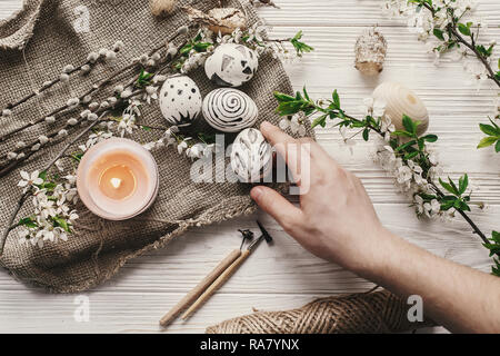 hand holding modern easter egg top view on rustic background. preparation for holiday, easter celebration. stylish painted egg.. family traditions. fl Stock Photo