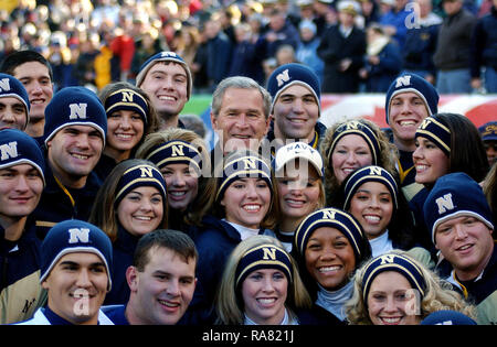 2004 - US President George W. Bush huddles with the Cheerleaders from the US Naval Academy (USNA) on the sidelines during opening ceremonies for the 105th Army vs. Navy game. The Navy Midshipman defeated Army 42 to 13. Stock Photo