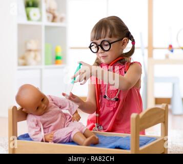 Child little girl playing with toy doll in nursery