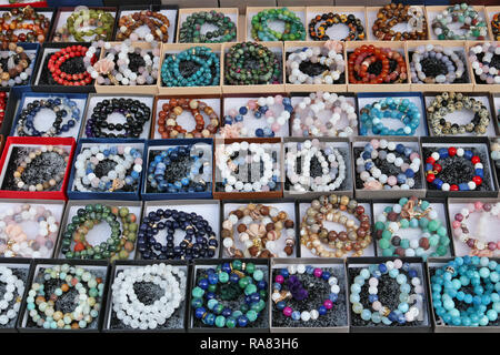 Beads and bracelets made of round stones and glass are sold on the street during the fair. Mass no name production Stock Photo