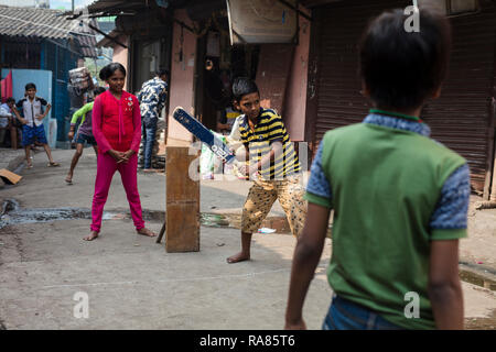 Mumbai, Maharashtra / India - December 12 2017: Children playing so-called „gully cricket“ in a small street in a slum in Mumbai. Stock Photo