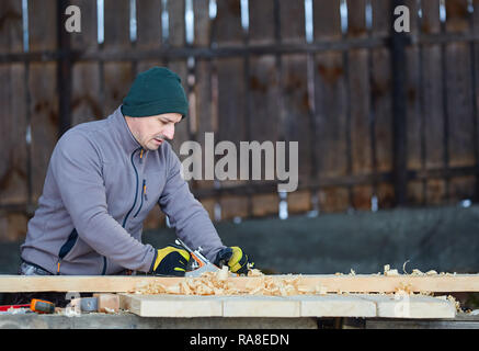 Woodworking - man using hand planer on a pine wood Stock Photo